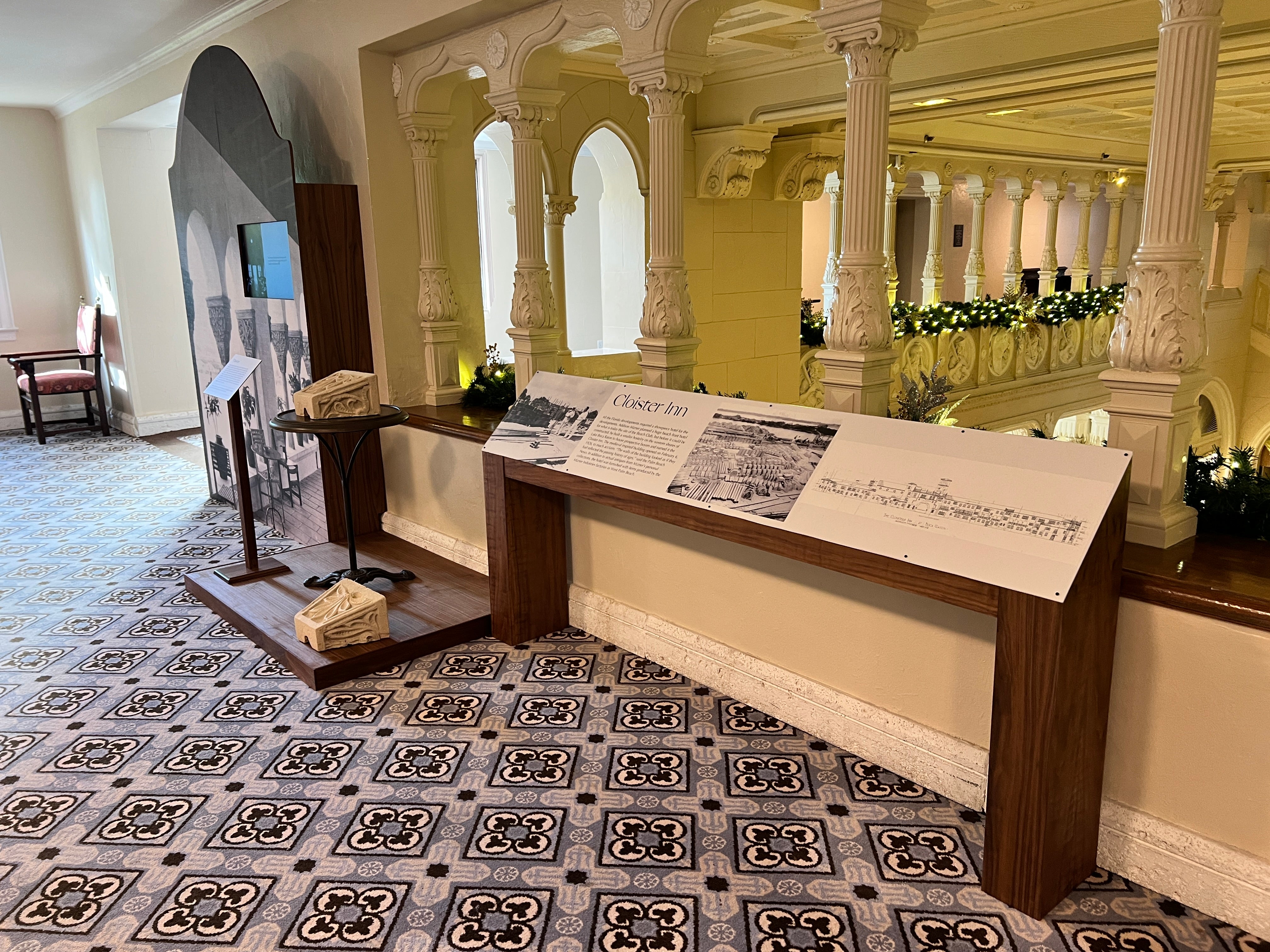 Historical exhibit with informational panels and decorative elements in a grand hall. The Boca Raton Mizner Museum - Cloister Inn Museum
