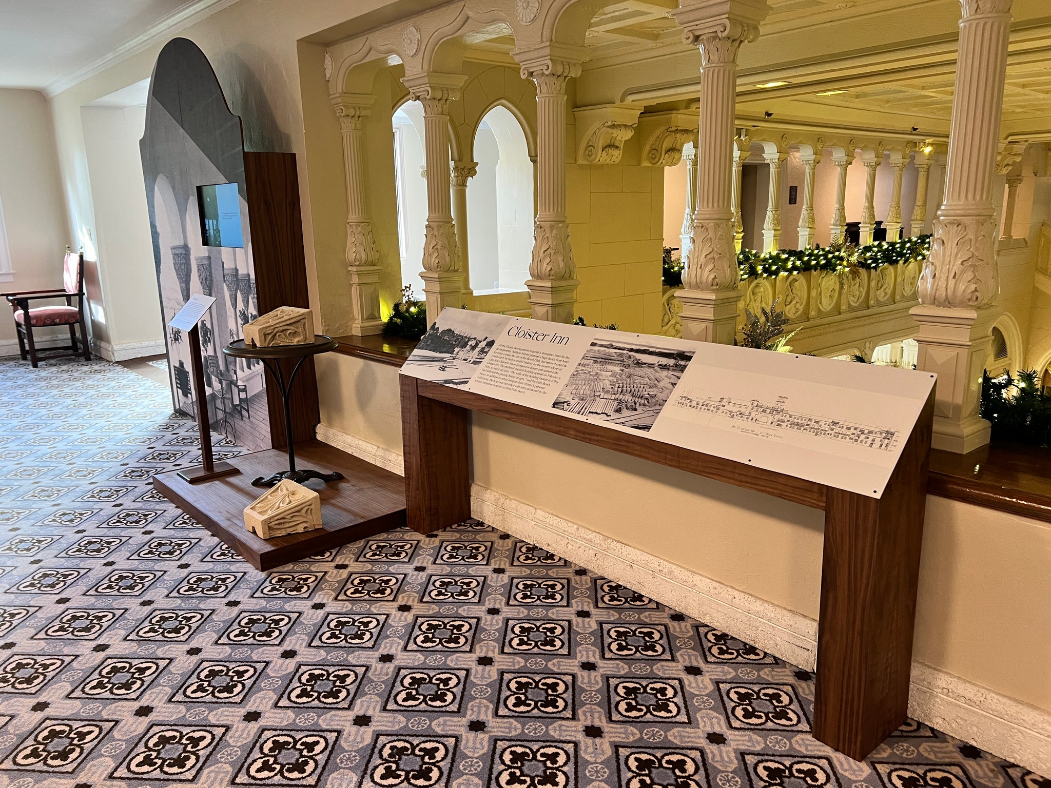 Historical exhibit with informational panels and decorative elements in a grand hall. The Boca Raton Mizner Museum - Cloister Inn Museum